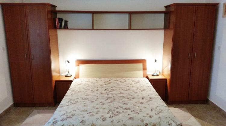 Bedroom with a double bed and built-in wardrobes in a hotel, Budva, Montenegro. Cozy interior with bedside lamps.
