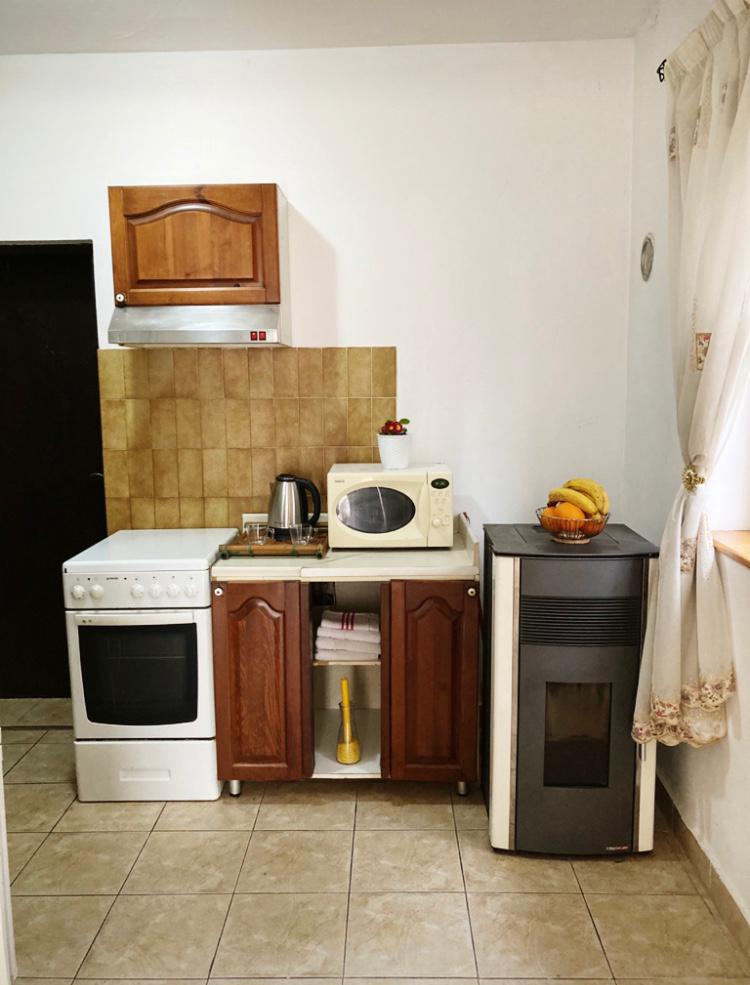 Compact kitchen with wooden cabinetry, a stove and an oven in a hotel in Budva, Montenegro. Cozy apartment interior.