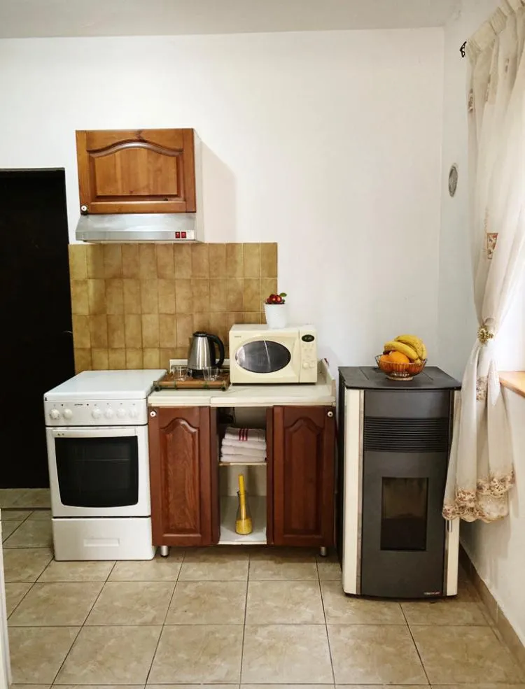 Kitchen with white stove, wooden cabinets, microwave, and kettle on the counter.