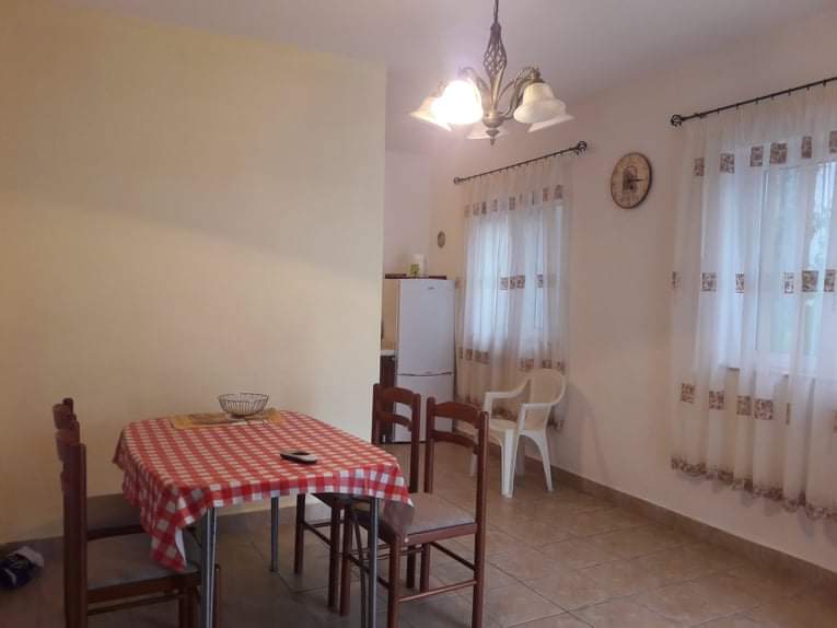 Cozy dining area with kitchen in a hotel in Budva, Montenegro: wooden table, chairs, and a bright interior.
