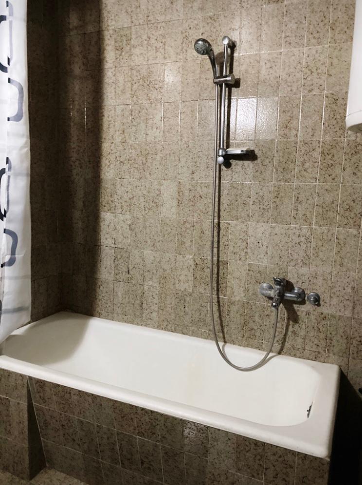 Bathroom with a white bathtub and beige tile finish in a hotel in Budva, Montenegro.