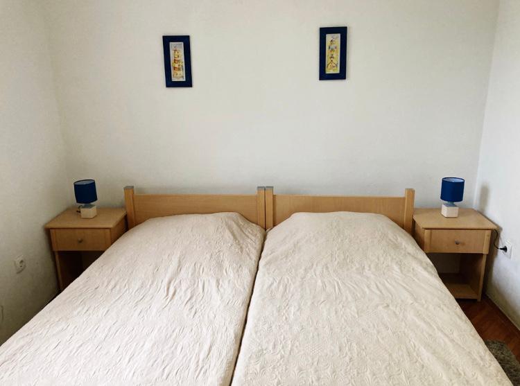 Bedroom in a hotel in Budva, Montenegro: a double bed with a wooden headboard, nightstands, and blue lamps.