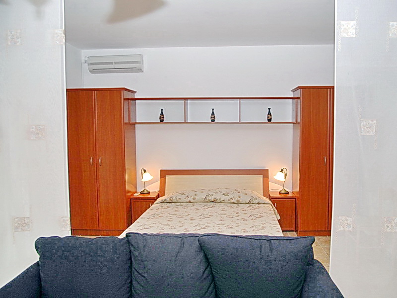 Hotel bedroom in Budva, Montenegro: double bed, wooden furniture set, bedside lamps, and air conditioning.