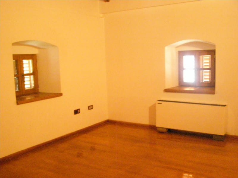 Bright living room with wooden windows and parquet flooring in a villa in Stoliv, Montenegro. Cozy interior with a radiator.