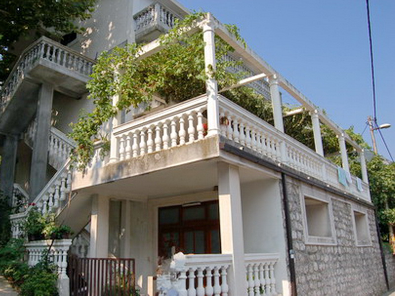 Two-story villa in Prčanj, Montenegro, with stone cladding, a spacious terrace, and a pergola covered in greenery.