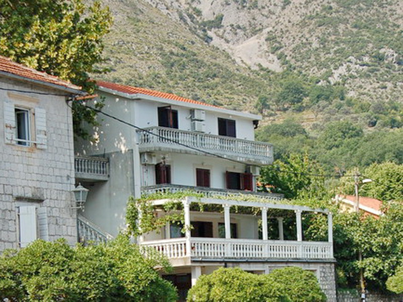 Three-story villa in Prčanj, Montenegro, with terraces, stone finishes, and mountain views surrounded by greenery.