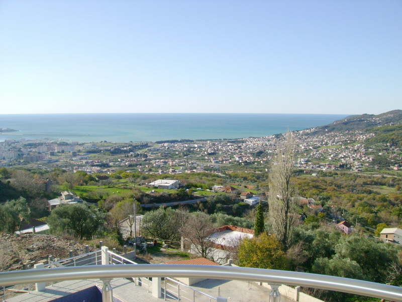 Panoramic view of the sea and the city of Bar, Montenegro, from the villa balcony with a metal railing and a pool.