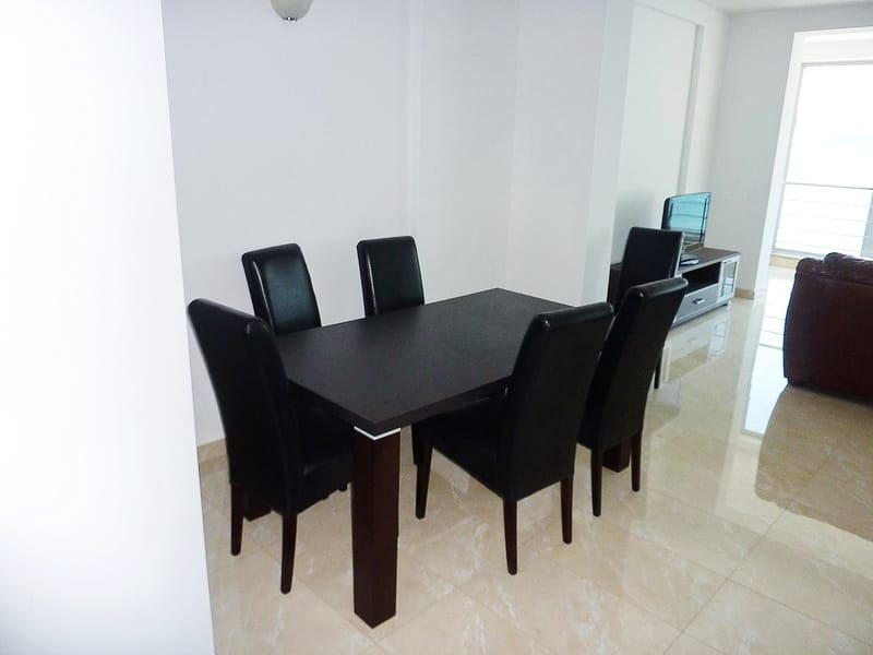Dining area with a dark table and chairs in a modern apartment in Rafailovici, Montenegro, bright interior.