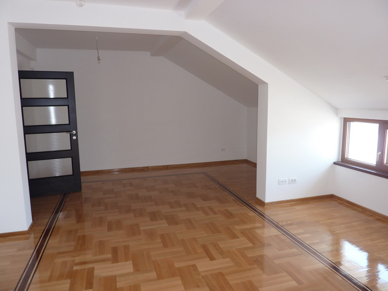 Bright living room in a loft apartment in Budva, Montenegro: parquet flooring, white walls, and a dark interior door.