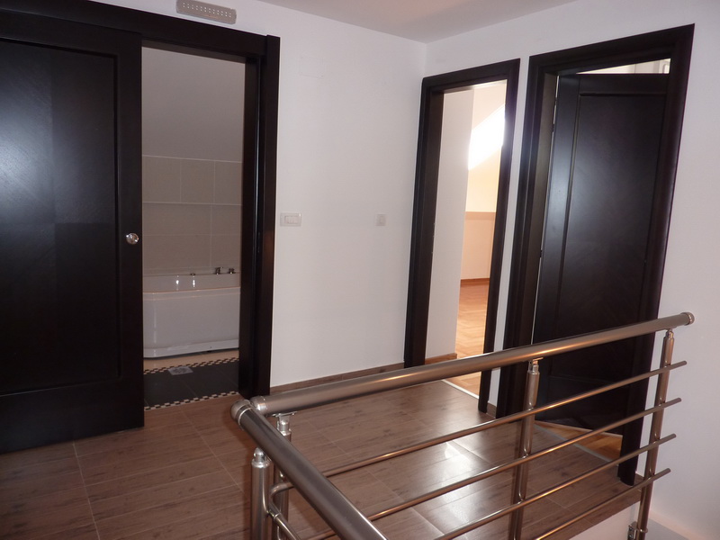 Apartment interior in Budva, Montenegro: a bright hallway with dark interior doors and a view of the bathroom.