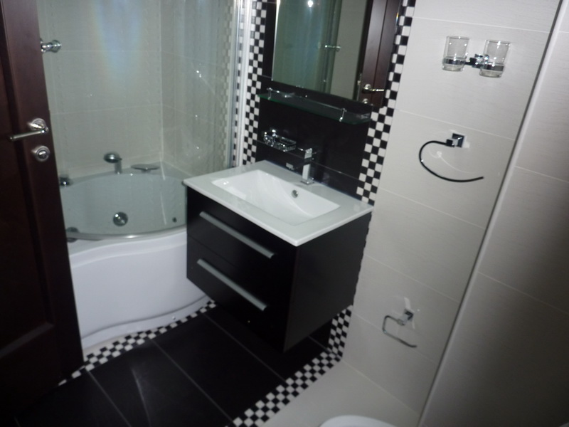 Modern bathroom in an apartment in Budva, Montenegro: corner bathtub, stylish vanity with sink, and decorative tile accents.