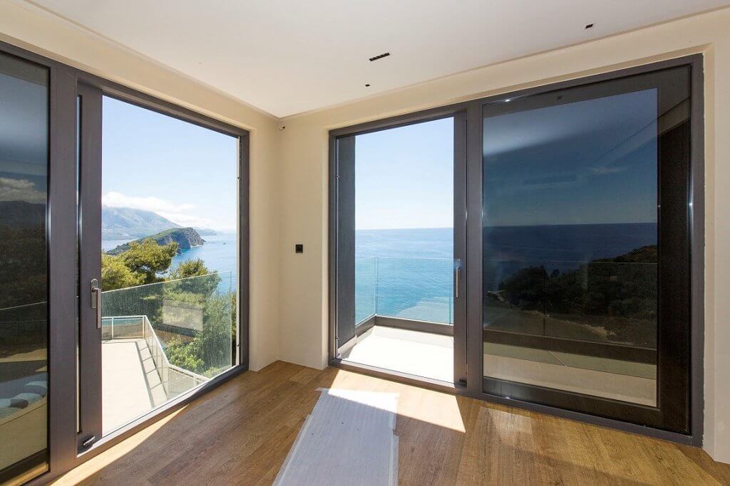 Living room with panoramic windows and sea view in an elite villa in Budva, Montenegro: modern interior, terrace.