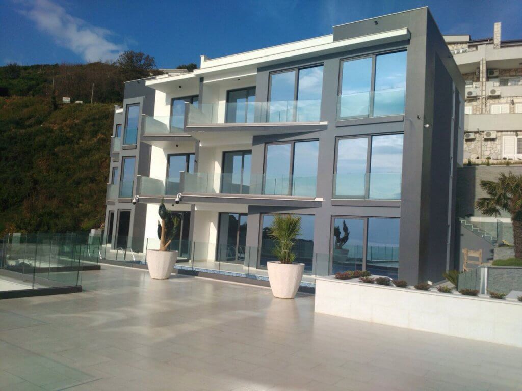 Modern villa in Budva, Montenegro: facade with panoramic windows, glass balconies, and a poolside terrace.