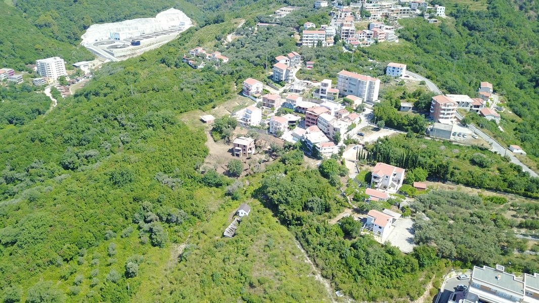 Aerial view of a land plot and residential development in Bečići, Montenegro, among hills and lush greenery.