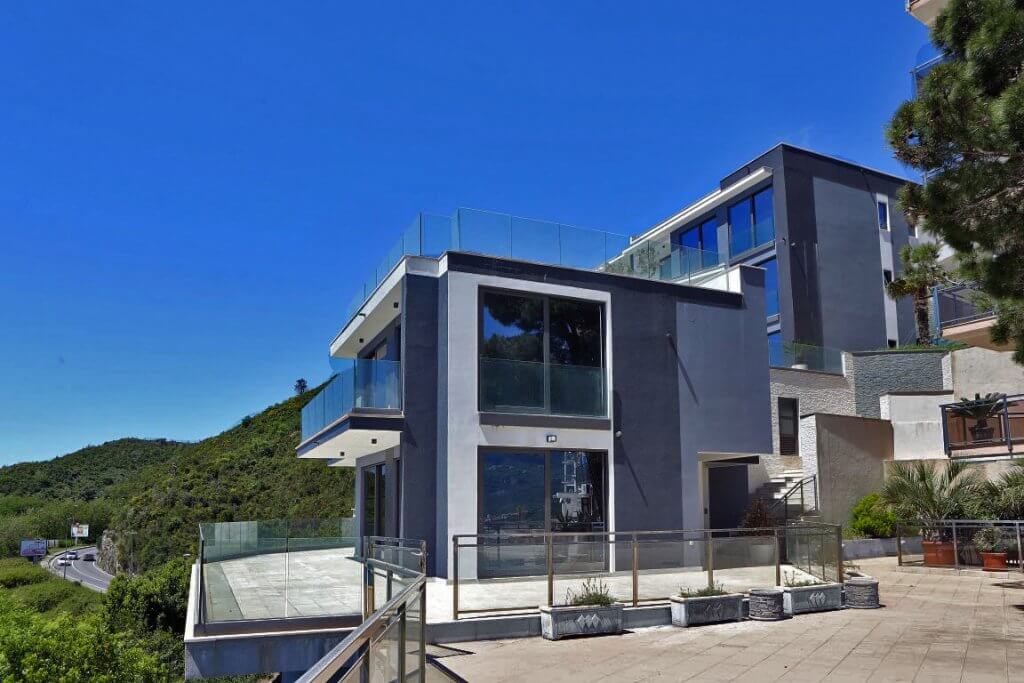 Modern villa with panoramic windows and terraces in Budva, Montenegro: view of the facade and surrounding grounds.