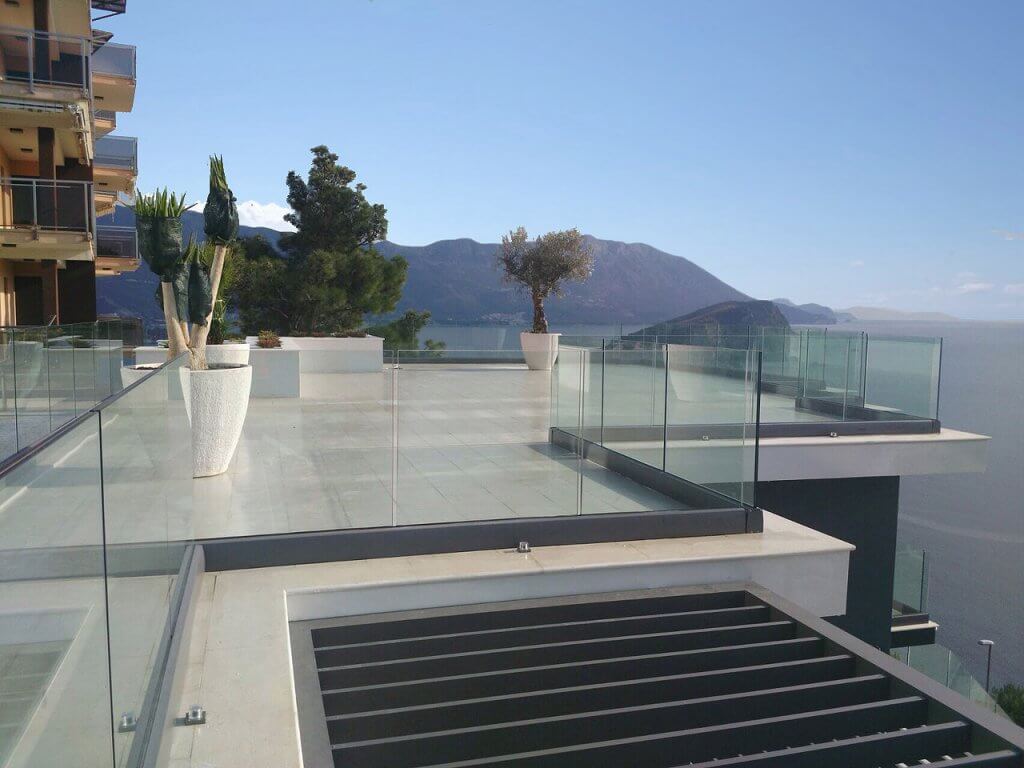 Spacious villa terrace in Budva, Montenegro, with glass railing, floor tiles, and panoramic sea views.