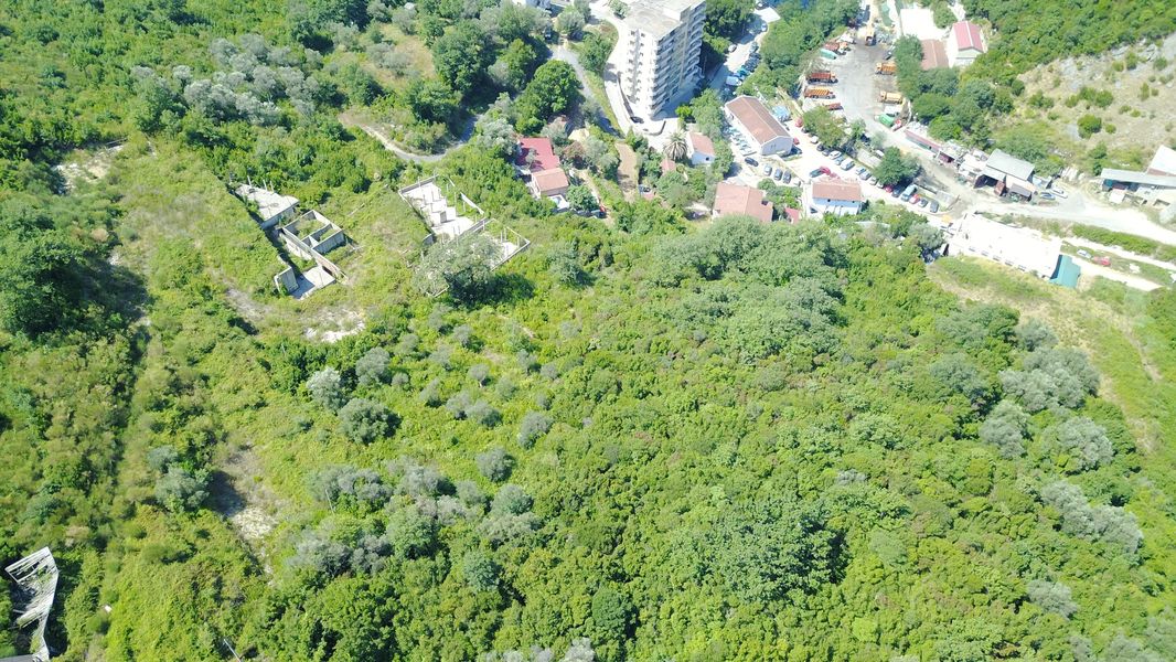 Building plot in Bečići, Montenegro: aerial view of the area with dense greenery and infrastructure.