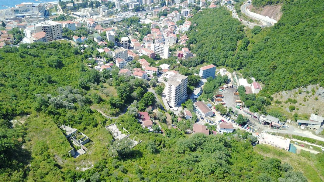 Aerial view of a plot of land and residential development in Bečići, Montenegro, with a panorama of the mountains and sea.