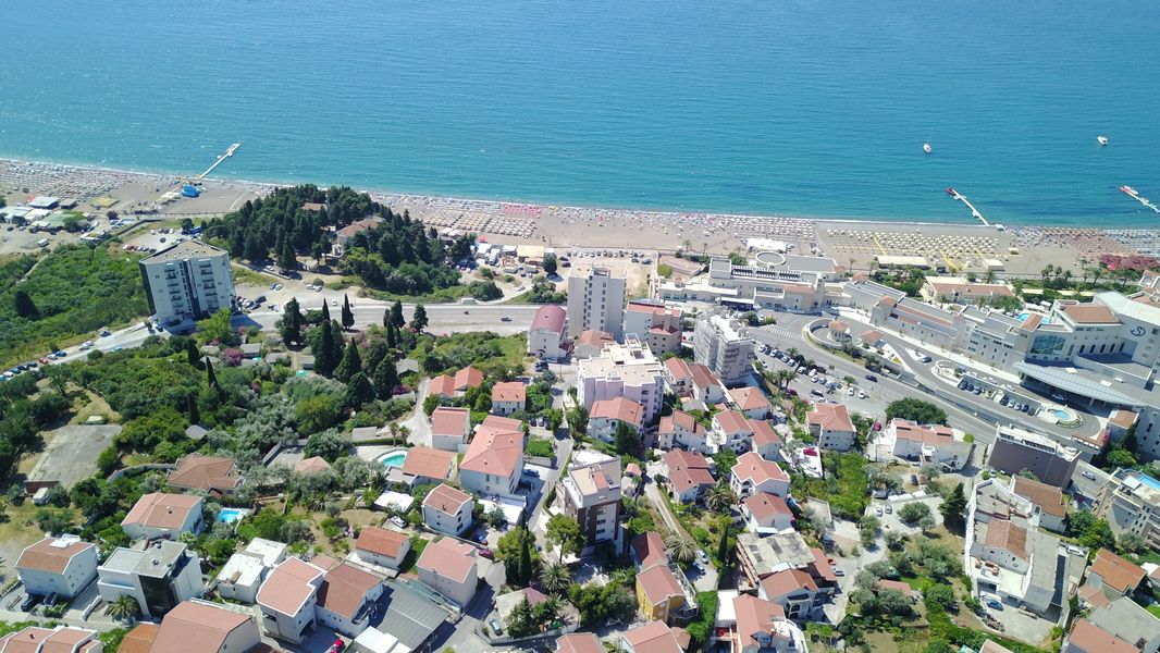 Aerial view of a plot of land in Bečići, Montenegro: a panorama of the coastline, beach, and seaside urban development.