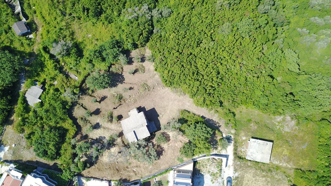 Building plot in Bečići, Montenegro: aerial view of the site with a house and greenery.