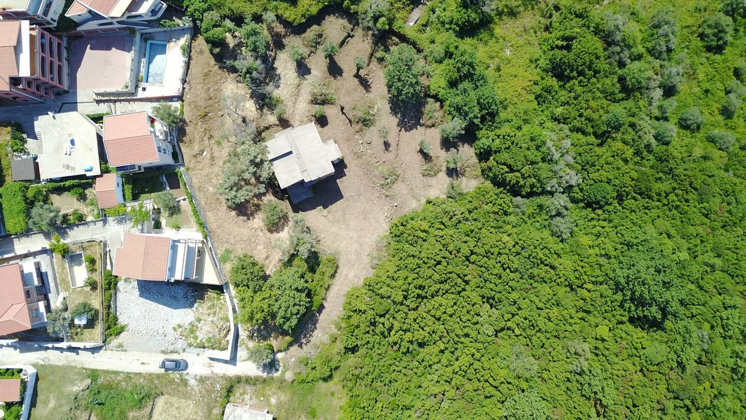Building plot in Bečići, Montenegro: aerial view of the area with a house and greenery.