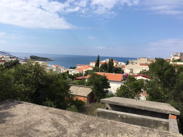 Panoramic view of the sea and the village of Uteha in Montenegro from a plot of land surrounded by greenery and trees.
