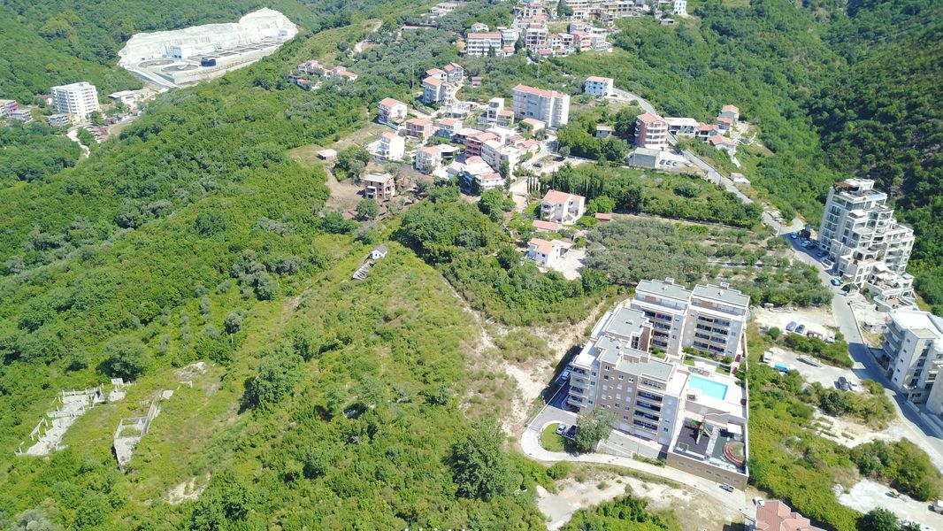 Aerial view of a land plot and residential complex with a pool in Bečići, Montenegro. Panorama of the mountain landscape.