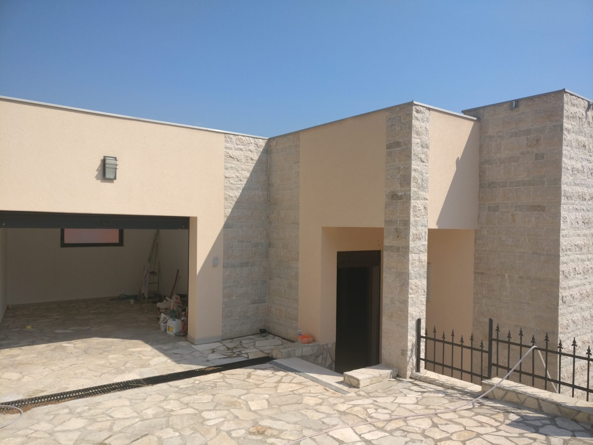 Modern house in Shushan, Montenegro: stone-clad facade, garage, and stone-paved surrounding area.