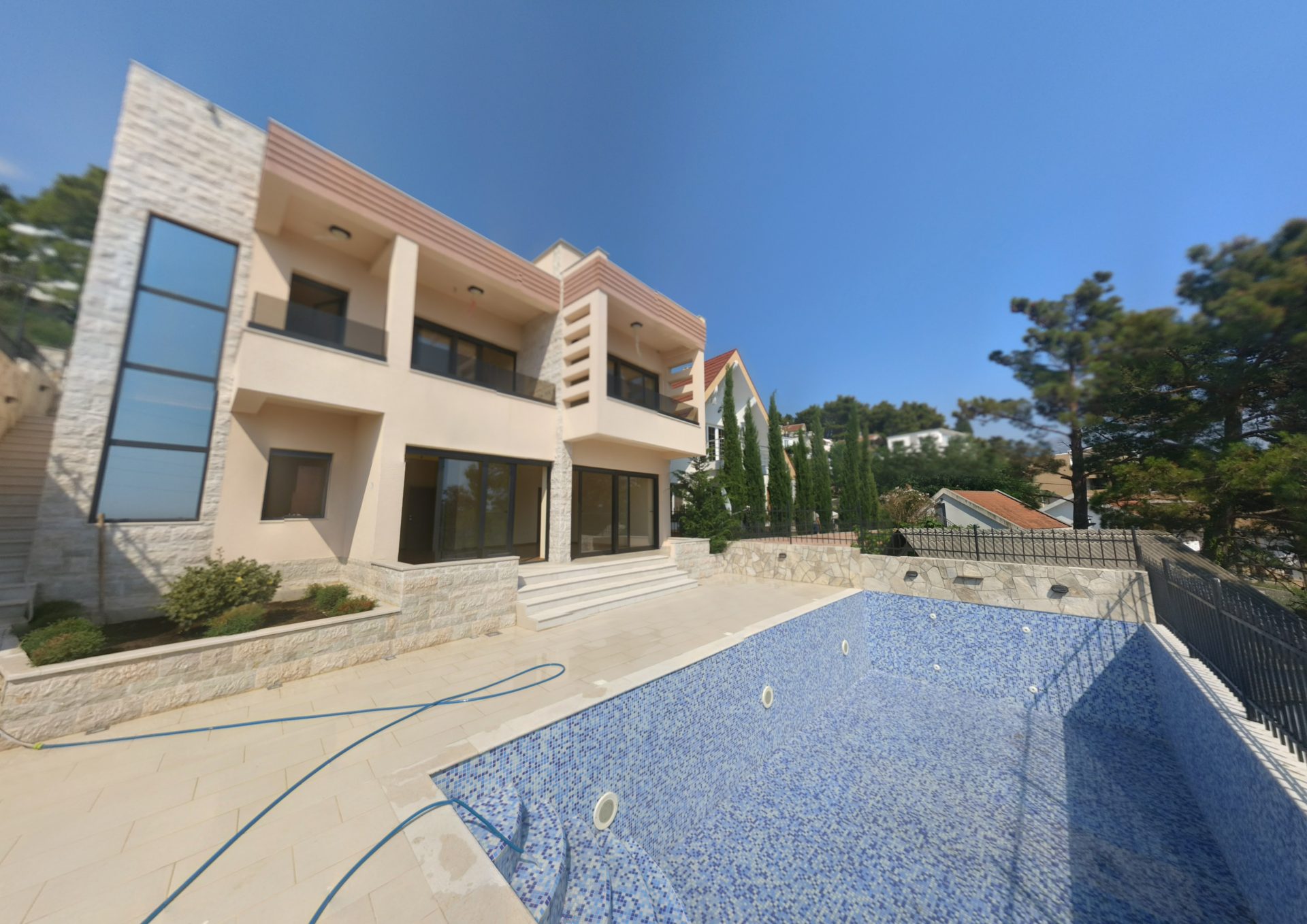 Modern villa with a pool and terrace in Shushan, Montenegro: stone facade, panoramic windows, and landscaped grounds.