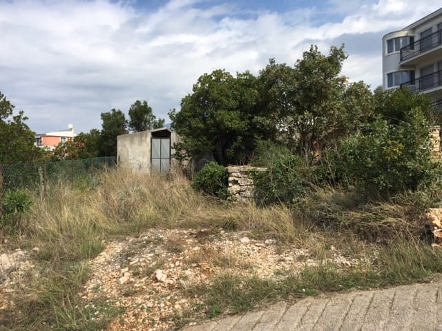 Building plot in Utjeha, Montenegro: view of the grounds with trees, a building, and stone masonry.
