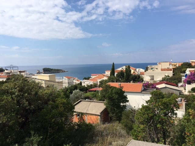 Panoramic view of the sea and the village of Utjeha in Montenegro from plot No. 414, surrounded by green trees.