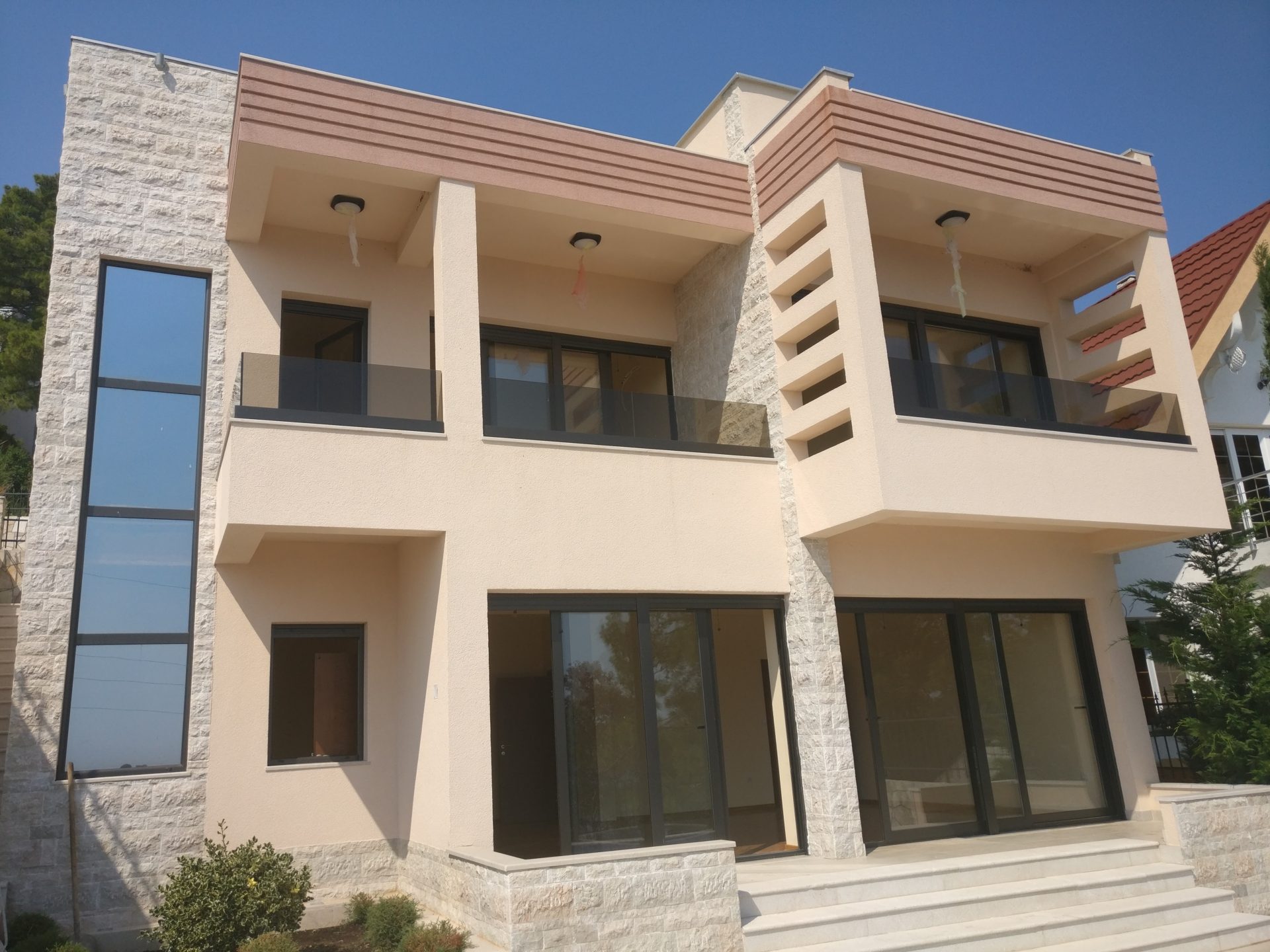 Modern two-story house with panoramic windows and terraces in Shushan, Montenegro — front view of the building.