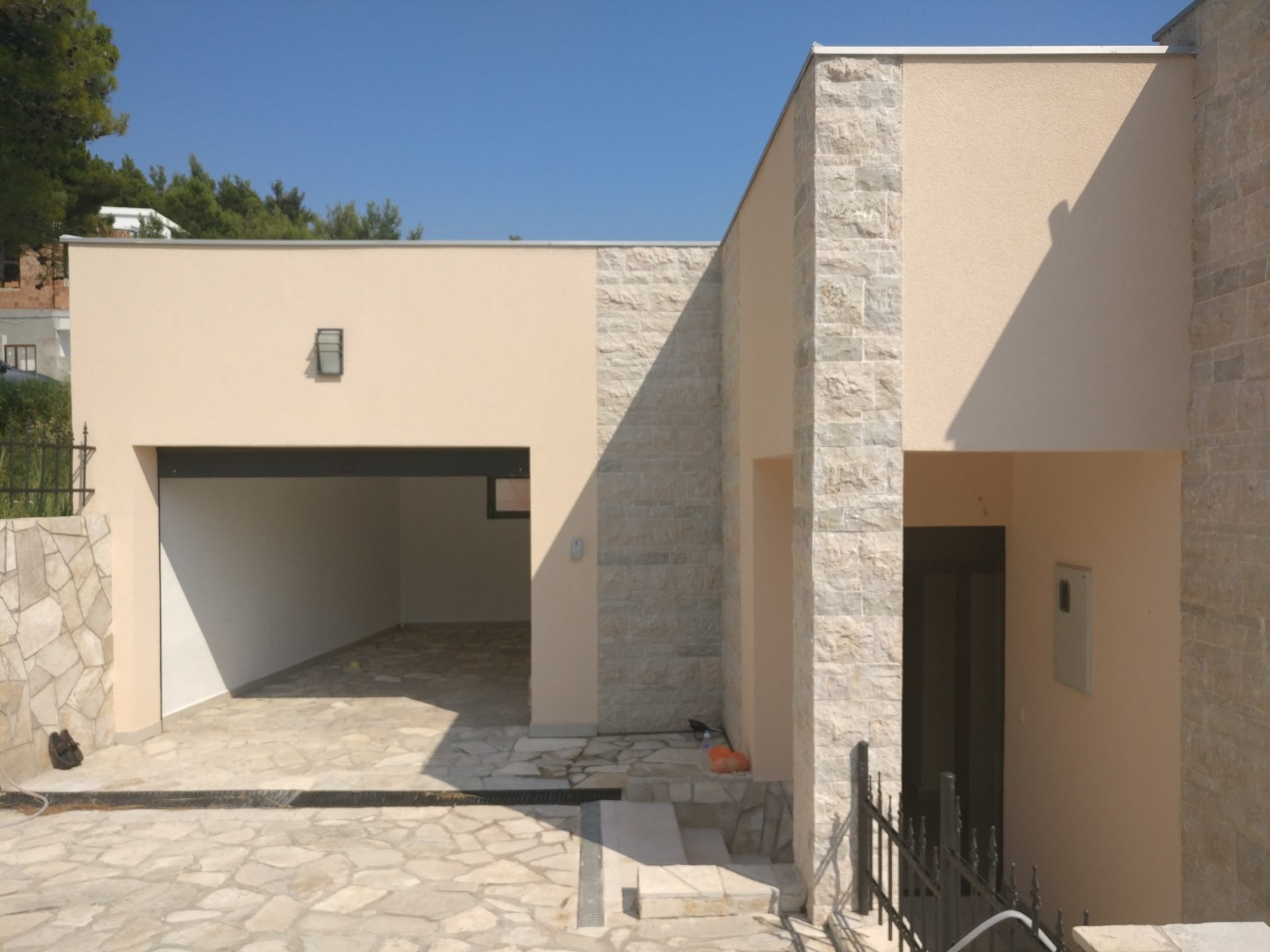 Modern house in Shushan, Montenegro: stone-clad facade, garage and entrance area, exterior view.