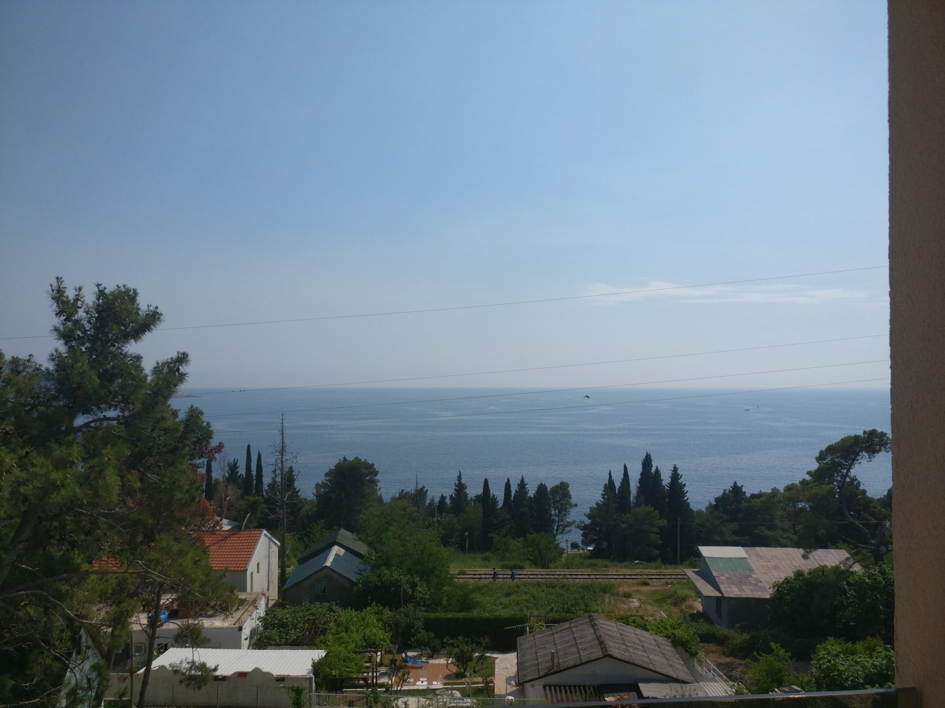 View of the Adriatic Sea from the balcony of a house in Šušanj, Montenegro: a panorama of the coastline, greenery, and private homes.