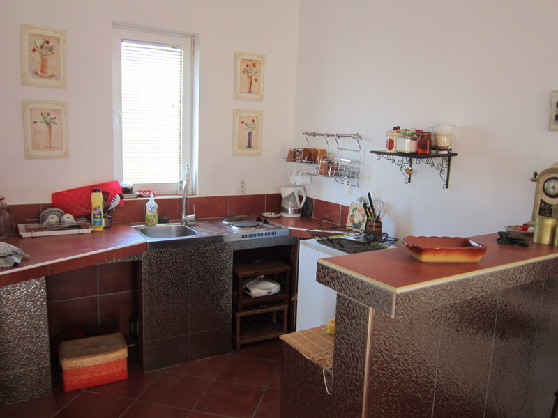 Kitchen in a house in Utjeha, Montenegro: terracotta-colored tile, a breakfast bar, and a compact cooking area.