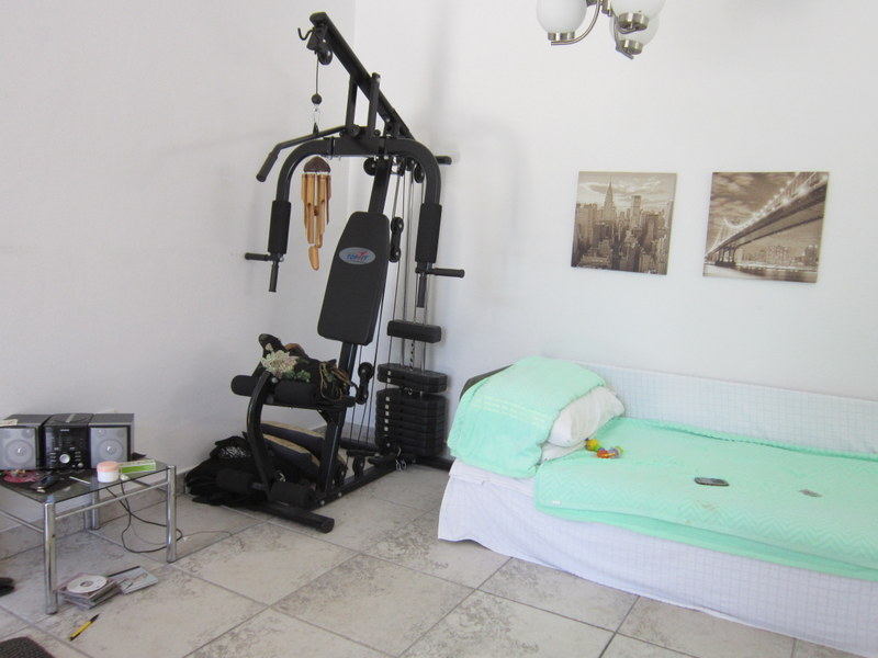 Bedroom with exercise equipment and a bed in a house for sale in Utjeha, Montenegro. Bright room with tiled floor.