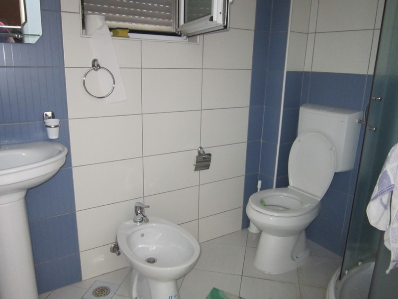 Bathroom in a house in Utjeha, Montenegro: white fixtures, bidet, shower cabin, and white-and-blue wall tiles.