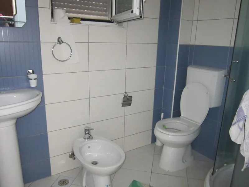 Bathroom featuring a toilet, bidet, pedestal sink, and blue and white wall tiles.