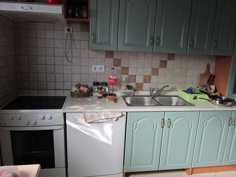 Kitchen in a house in Utjeha, Montenegro: light-colored cabinets, built-in stove, dishwasher, and stainless steel sink.