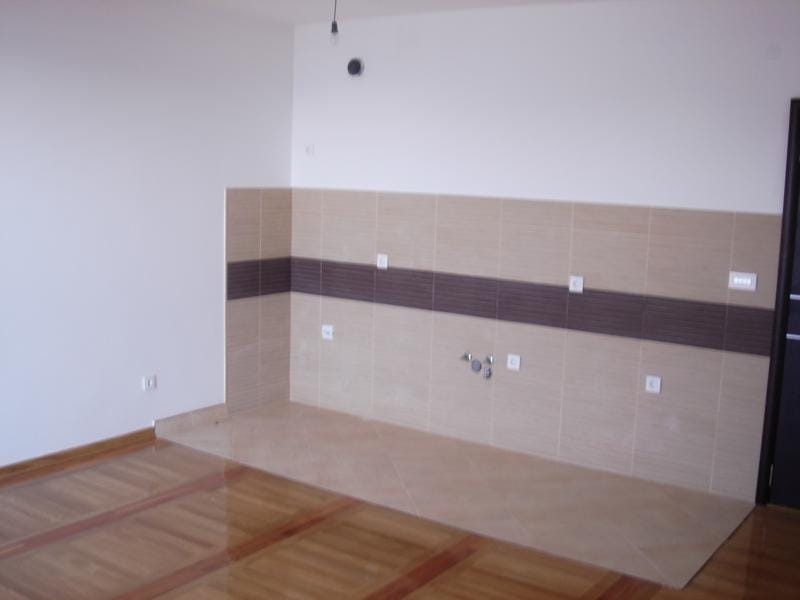 Kitchen area in an apartment in Miločer, Montenegro: light tiles, a decorative backsplash, and parquet flooring.