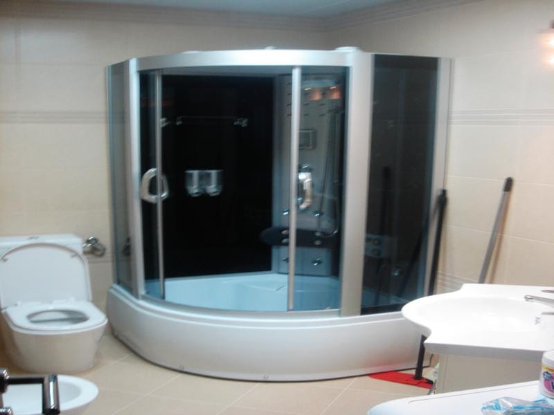 Bathroom in an apartment in Miločer, Montenegro: modern hydromassage shower cabin, plumbing fixtures, and light-colored tiles.