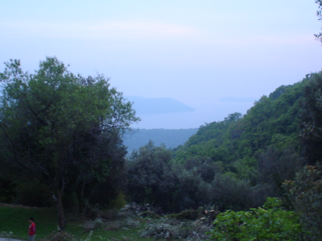 Scenic sea and mountain view from a plot of land in Herceg Novi, Montenegro, surrounded by lush greenery.
