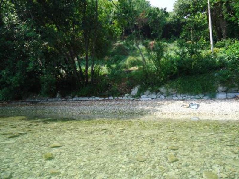 A seaside plot with a pebble beach and lush greenery in Kostanica, Montenegro.