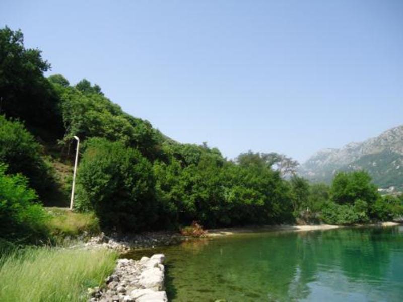 Land plot by the sea in Kostanica, Montenegro: view of the coastline, green hills, and mountains in the Bay of Kotor.