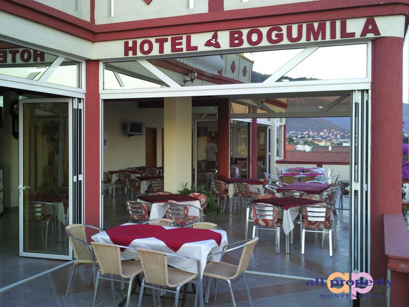 Open terrace of the Bogumila hotel restaurant in Bar, Montenegro, with tables and panoramic mountain views.
