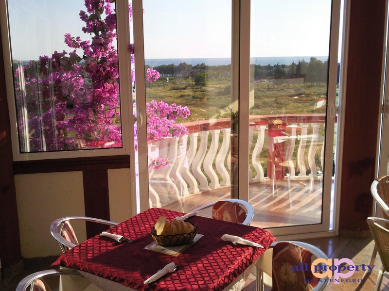 Sea view and terrace with blooming bougainvillea from the hotel living room in Bar, Montenegro. A table set by the window.