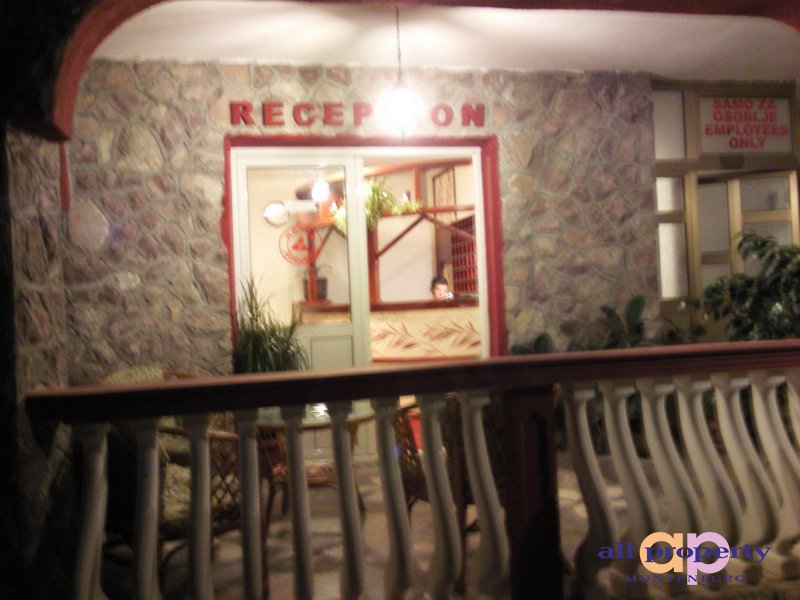 Hotel reception desk in Bar, Montenegro: stone facade finish, terrace with balustrade, and wicker furniture.