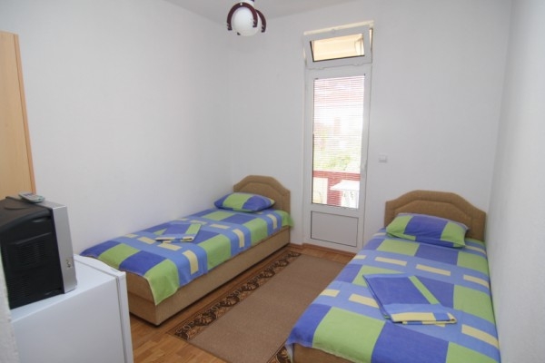 Bedroom with two single beds in a hotel in Bar, Montenegro, with access to a balcony and light finishes.