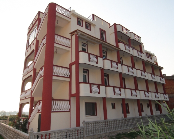 Facade of a four-story hotel in Bar, Montenegro, with white balconies and red columns on the exterior.