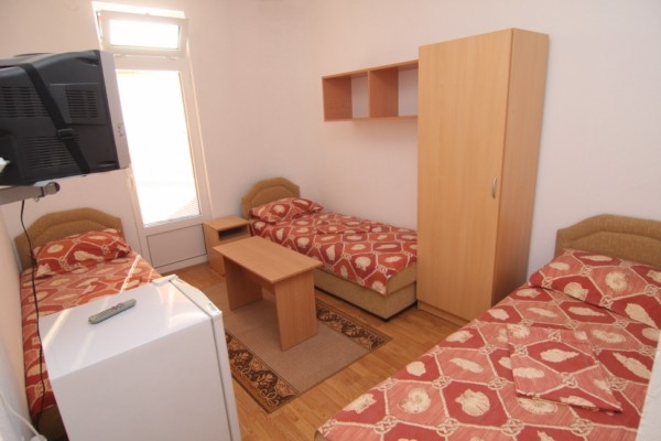 Triple room in a hotel in Bar, Montenegro: three beds, a wardrobe, a refrigerator, a TV, and access to the balcony.